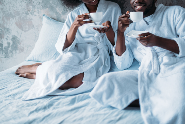 Cropped image of young african american couple drinking coffee in bed - Foto, afbeelding