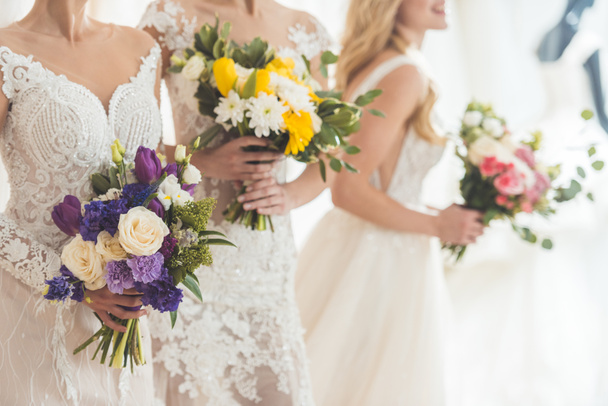 Close-up view of brides in lace dresses with flowers in wedding fashion shop - Foto, Imagen