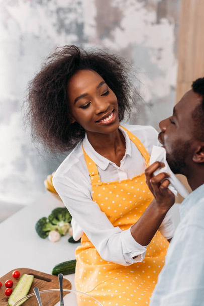 Smiling african american wiping mouth of boyfriend by napkin - Foto, afbeelding