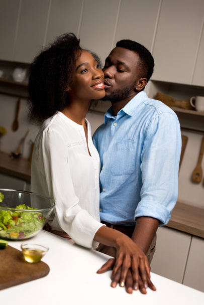 Man kissing young smiling woman in kitchen  - Photo, Image