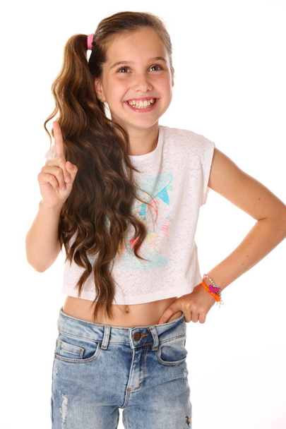 Portrait of happy slender cheerful teenage girl. The child elegantly poses makes funny faces and smiles. Young fashionista in blue jeans and with a bare belly. - Fotoğraf, Görsel