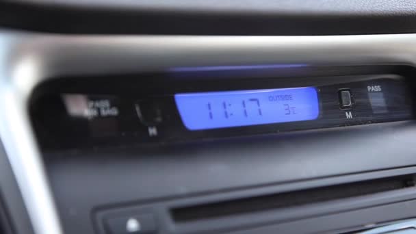 een video van een hand druk op de knop uur op de klok van een auto om de tijd te veranderen  - Video