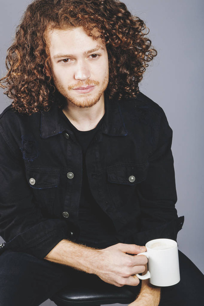 Young athletic ginger man holding a coffee mug, studio portrait - 写真・画像