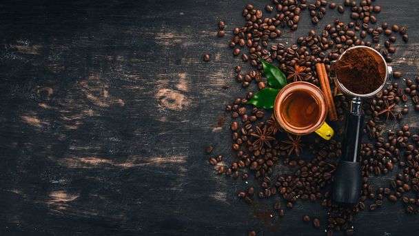 Hot espresso coffee in a cup. Cinnamon. On a black wooden background. Top view. Copy space. - 写真・画像