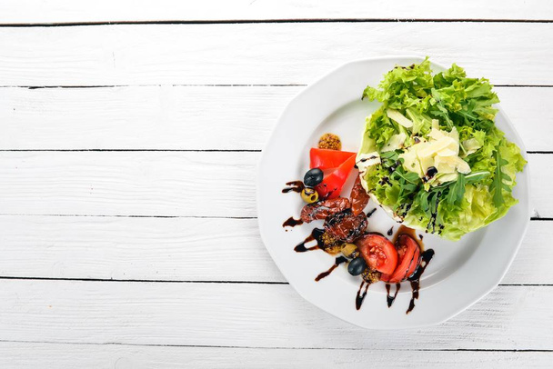 Salad with tomatoes, arugula and smoked tomatoes. On a wooden background. Top view. Copy space. - Фото, изображение