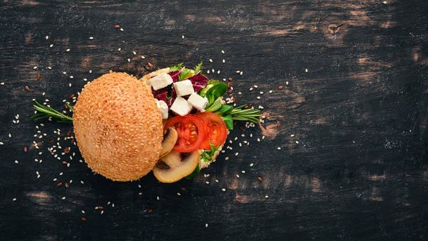 Burger, sandwich with feta cheese, mushrooms and lettuce leaves. On a wooden background. Top view. Copy space. - Photo, Image