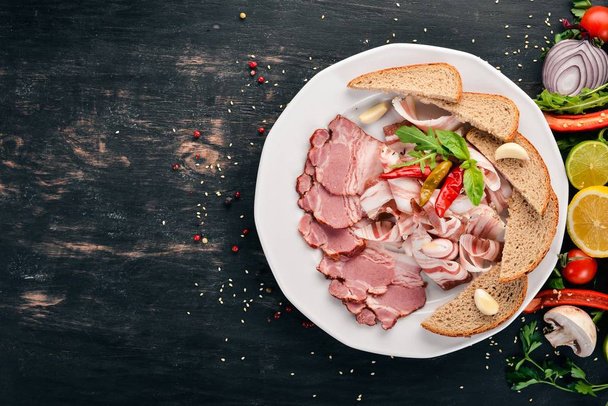 Slice of smoked meat on a plate. On a wooden background. Top view. Copy space. - Photo, image