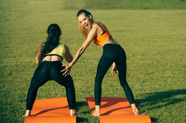 Energy women do athletic exercises on green grass - Valokuva, kuva