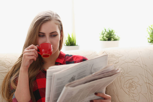 woman drinking coffe and reading sit on sofa - Foto, imagen