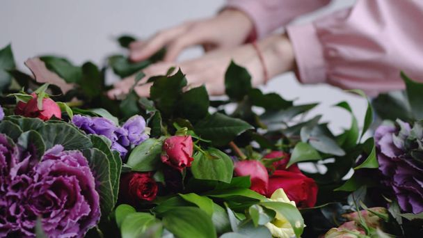 Флорист ставит красивые розы для оформления современного букета
 - Фото, изображение