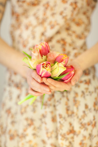 woman hands holding spring flowers tulips and roses, spring flower dress, sensual studio shot can be used as background - Foto, Bild