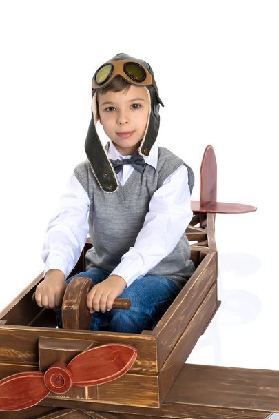 Μικρό αγόρι με ένα ξύλινο αεροπλάνο. - Φωτογραφία, εικόνα