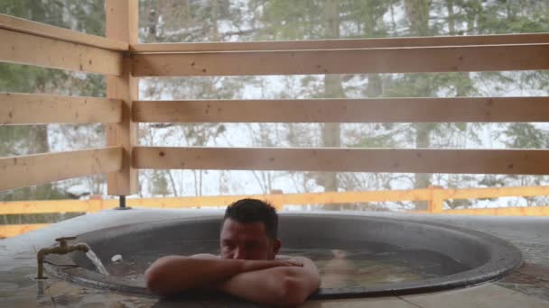 ein Mann badet im gusseisernen Bottich mit Mineralwasser und dreht den Wasserhahn mit kaltem Wasser zu. - Filmmaterial, Video