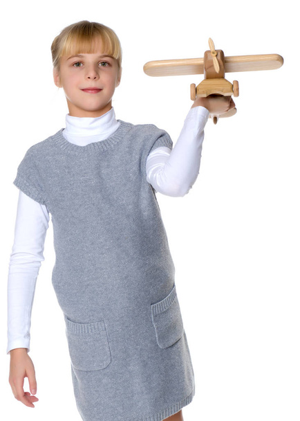 Little girl is playing with a wooden plane. - Foto, Bild