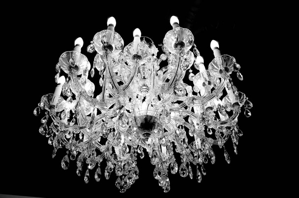 Kristal of glas kroonluchter aan het plafond met verlichting en kaarsen - Foto, afbeelding