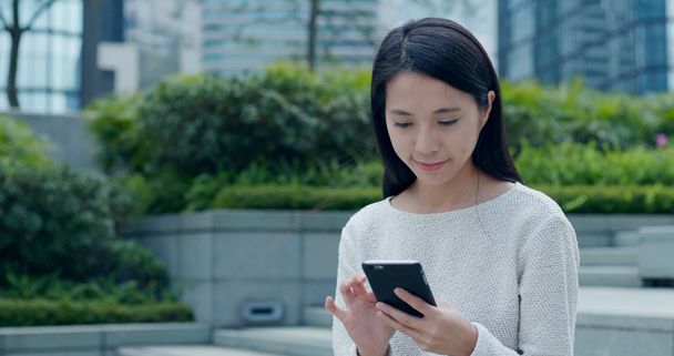 Mujer enviando SMS en el teléfono inteligente al aire libre
  - Foto, imagen