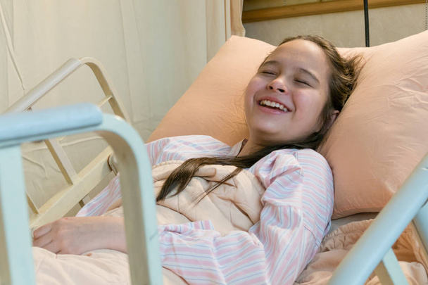Laughing mixed race tween girl in hospital bed - Foto, immagini