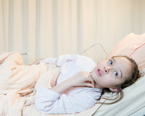 Mixed race tween girl in hospital bed - Foto, afbeelding