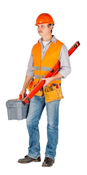 construction worker in a helmet  with toolbox and looking at camera over white wall background. repair, construction, building, people and maintenance concept. - Φωτογραφία, εικόνα