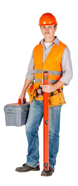 construction worker in a helmet  with toolbox and looking at camera over white wall background. repair, construction, building, people and maintenance concept. - Zdjęcie, obraz