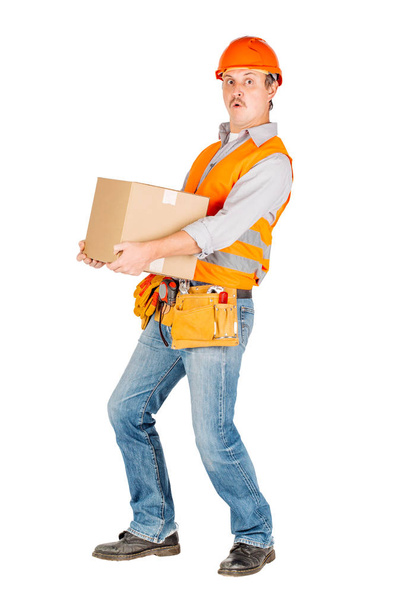 male builder or manual worker in helmet holding and moving  cardboard box on white background. repair, construction, building, people and maintenance concept - Foto, Bild