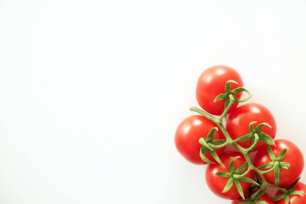 Minimalistic flat lay composition of shiny red cherry tomatoes reflecting light, laying on solid white table top. - 写真・画像