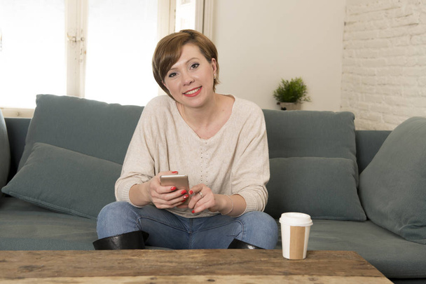 young attractive and happy red hair woman sitting at home sofa c - Photo, Image