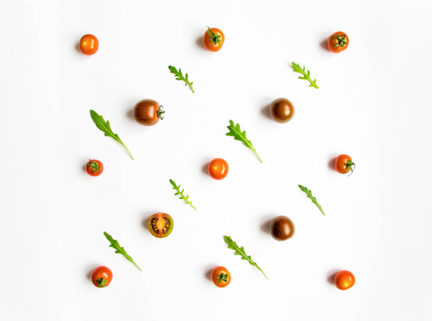 Tomates cherry y ensalada de rúcula patrón de hojas sobre fondo blanco. Puesta plana
 - Foto, Imagen