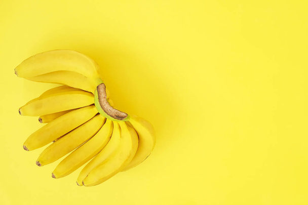 Beautiful minimlistic flat lay composition with ripe fresh organic bananas hand in warm yellow colors. Top view copy space, close up. - Foto, Imagen