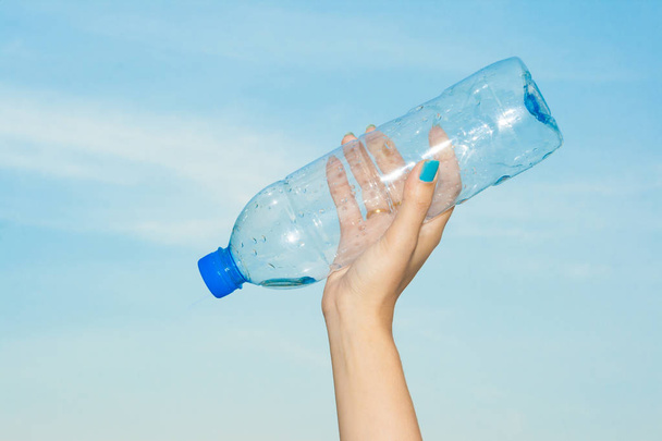 Жінка рука тримає пляшку води в небі
. - Фото, зображення