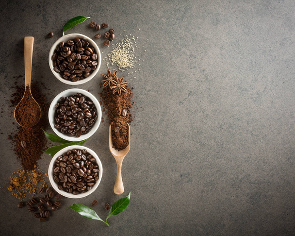 Διαφορετικές ποικιλίες των κόκκων καφέ με ζάχαρη και πράσινα φύλλα - Φωτογραφία, εικόνα