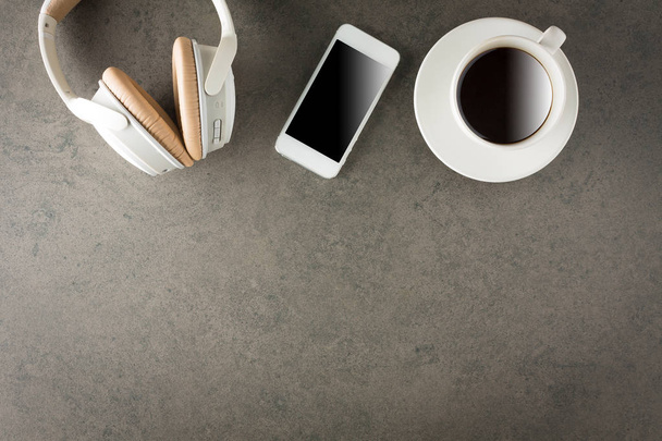 Samrtphone with headphone and cup of coffee on stone background. - Фото, изображение