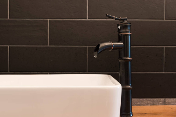 Modern white square sink in bathroom with black tiles and black faucet in shape of bamboo. Modern bathroom design - Φωτογραφία, εικόνα