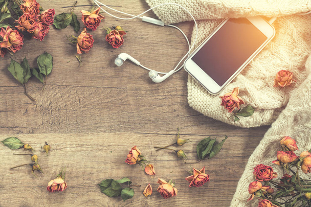 White knitting wool, dried roses flowers, mobile phone and headp - Φωτογραφία, εικόνα