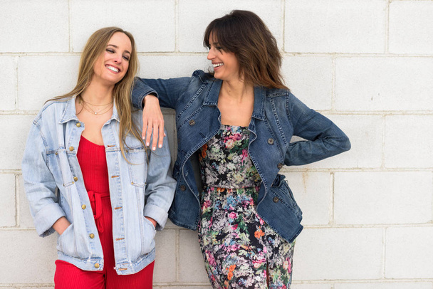 Duas jovens mulheres sorrindo em meio urbano
 - Foto, Imagem