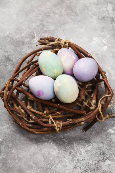 Multicolored eggs for Easter in nest on gray background. Top vie - Foto, Bild