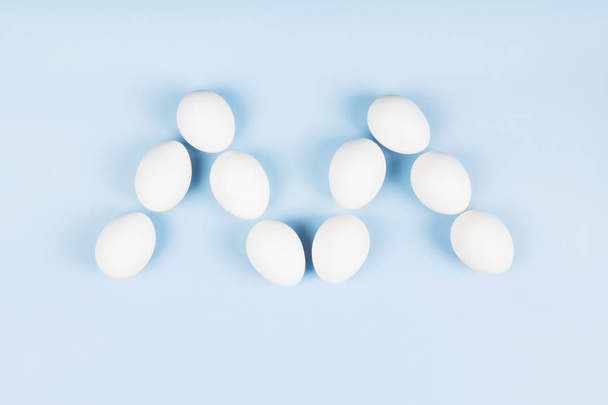 White eggs in form of letter "m" on blue background. Concept gen - Fotoğraf, Görsel