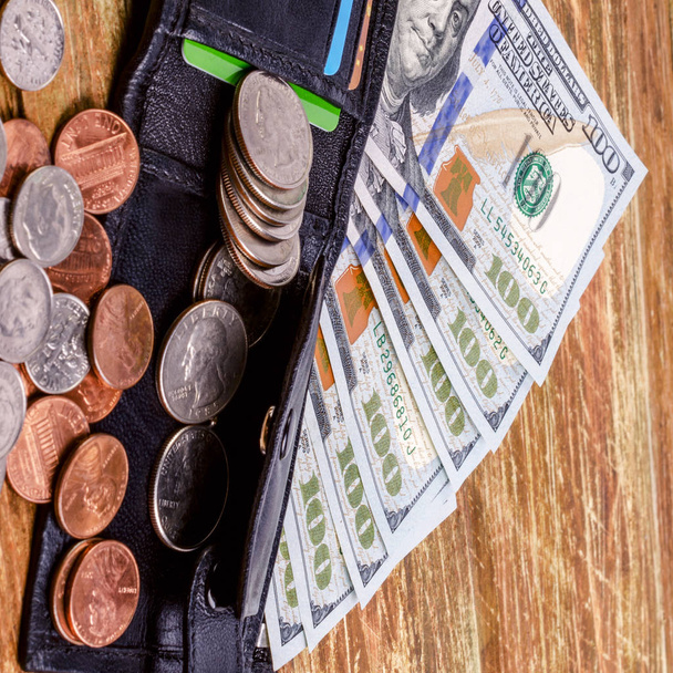 Billetera de cuero negro por encima de los billetes y monedas de Estados Unidos. Finanzas ba
 - Foto, Imagen