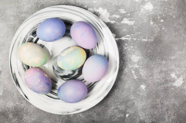 Multicolored eggs for Easter in marble plate on gray background. - Foto, Bild