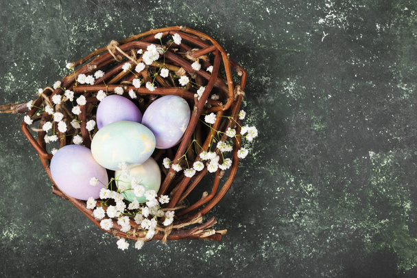 Multicolored eggs for Easter in nest with flowers on green backg - Valokuva, kuva