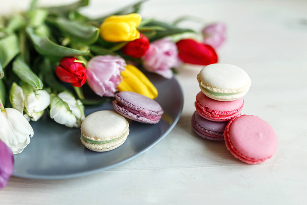 Macarons sur fond blanc en bois avec des tulipes de fleurs printanières
 - Photo, image