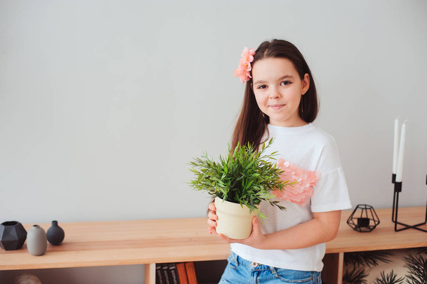 happy preteen girl taking care of houseplants at home - Foto, Imagem