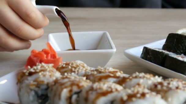 Japán ételt. Sushi tekercs hazugság, citrom és gyömbér wasabi mellett az asztalon. Szójaszósz ömlött ki egy különleges porcelán teáskanna a csészealj - Felvétel, videó