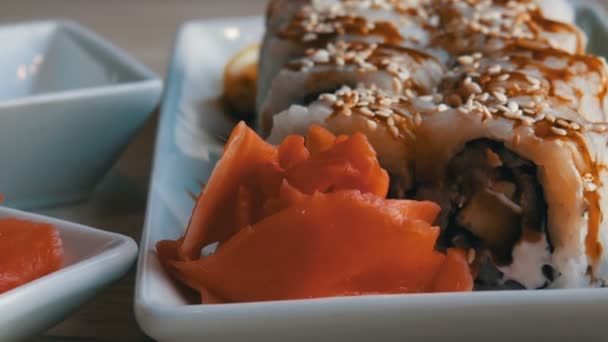 Japán ételt. Sushi tekercs hazugság, citrom és gyömbér wasabi mellett az asztalon. Szójaszósz ömlött ki egy különleges porcelán teáskanna a csészealj - Felvétel, videó