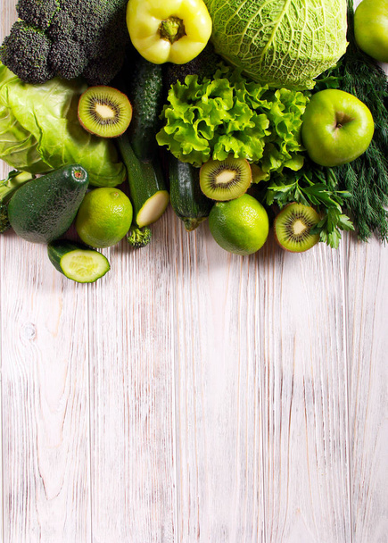 Green vegetables and fruits over wooden background - Foto, afbeelding
