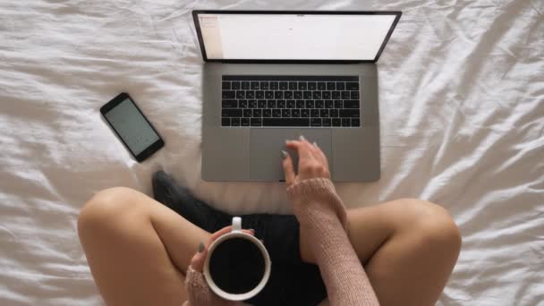 Beautiful young woman sitting at bed in the morning with cup of coffee and latop - Footage, Video