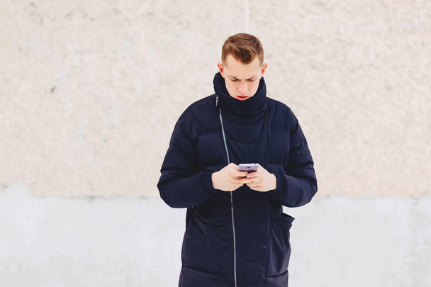 guy in winter jacket writes sms - Valokuva, kuva