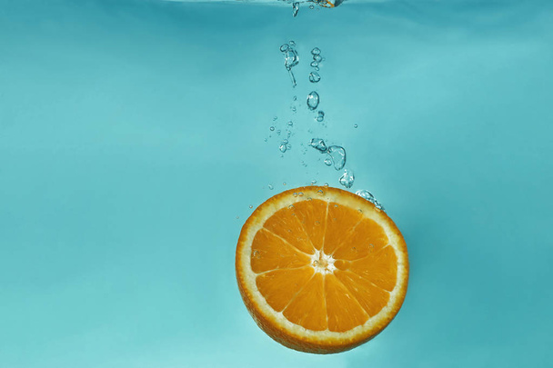 The orange fell under the water                                - Фото, изображение
