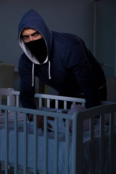 Criminal stealing baby in human child traficking concept - Photo, Image