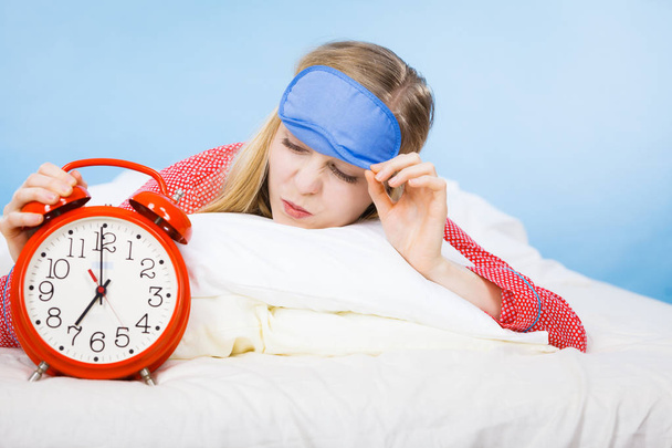 Sleeping woman wearing pajamas holding clock - Фото, зображення